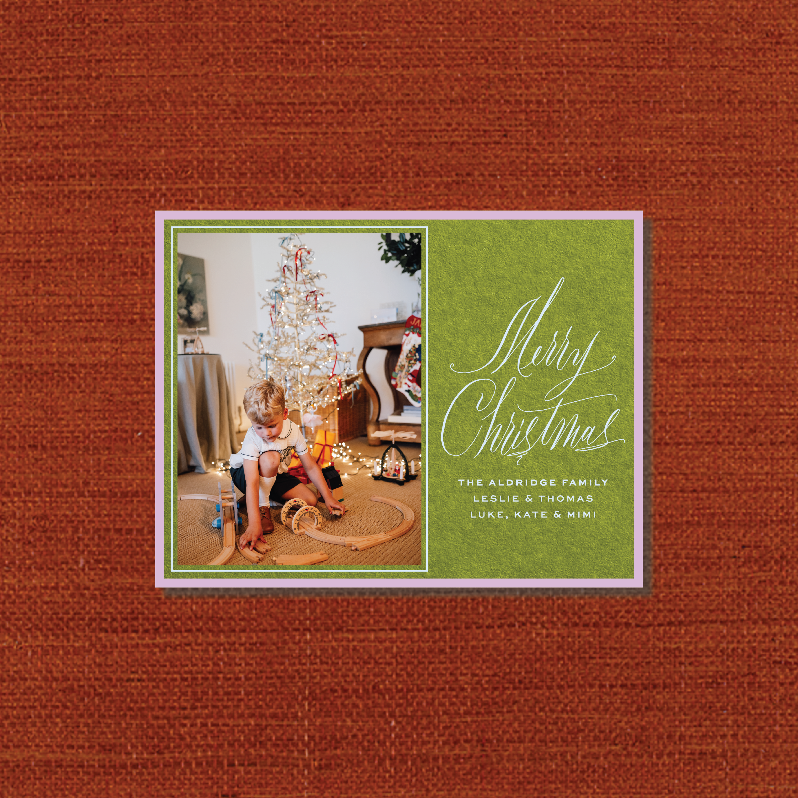 Aldridge Engraved Christmas Photo Card featuring a family photograph beside hand-lettered “Merry Christmas” calligraphy on a rich red background with personalized family names.