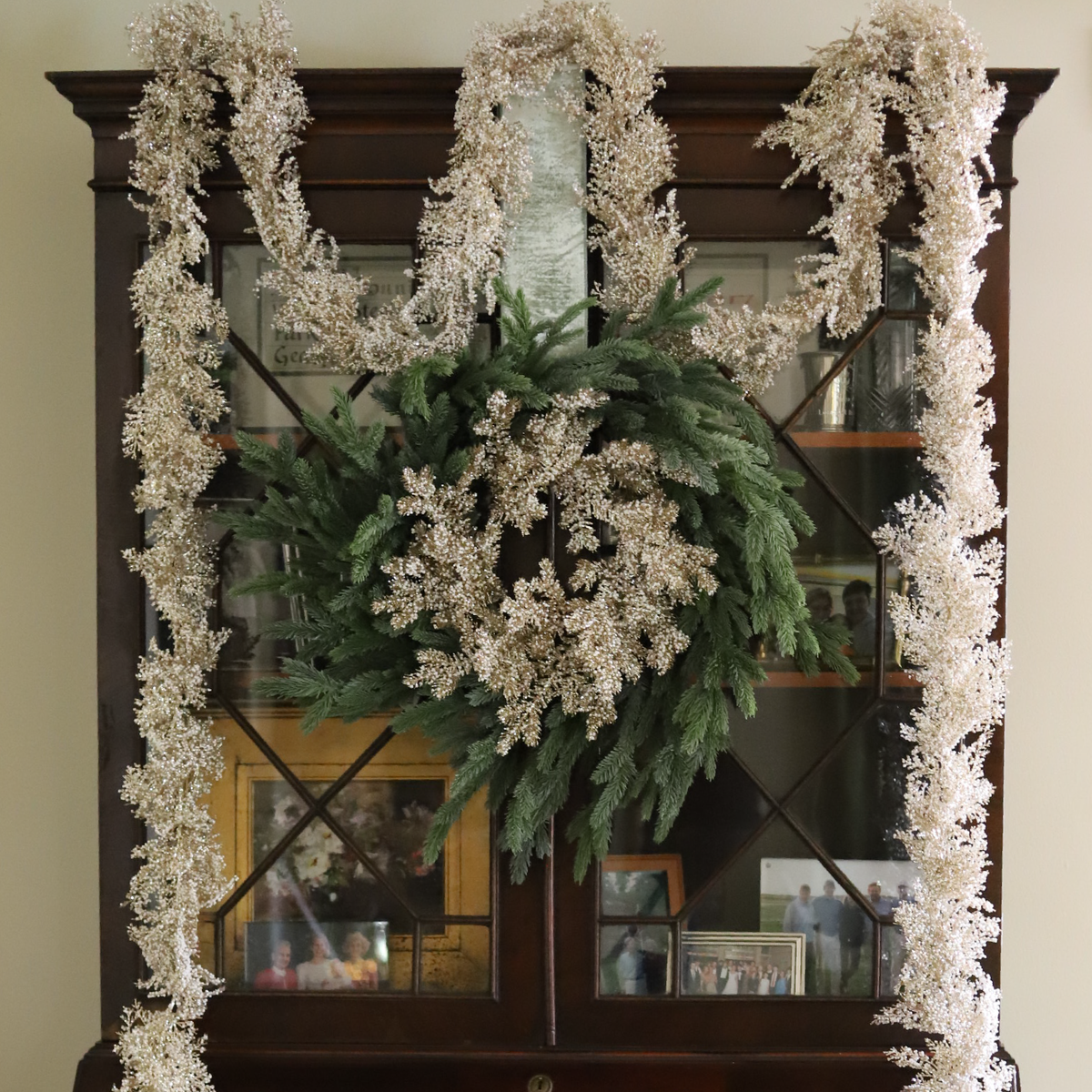 Chatsworth Champagne Wreath layered with a Cotswold Fir Wreath and Chatsworth Champagne Garland on an antique cabinet