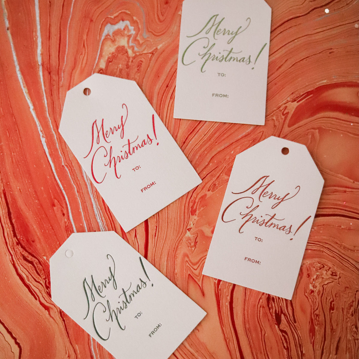 Shop Merry Christmas Gift Tags in sets of 8, featuring elegant hand-lettered lettering, To and From lines, and coordinating color options for holiday wrapping.