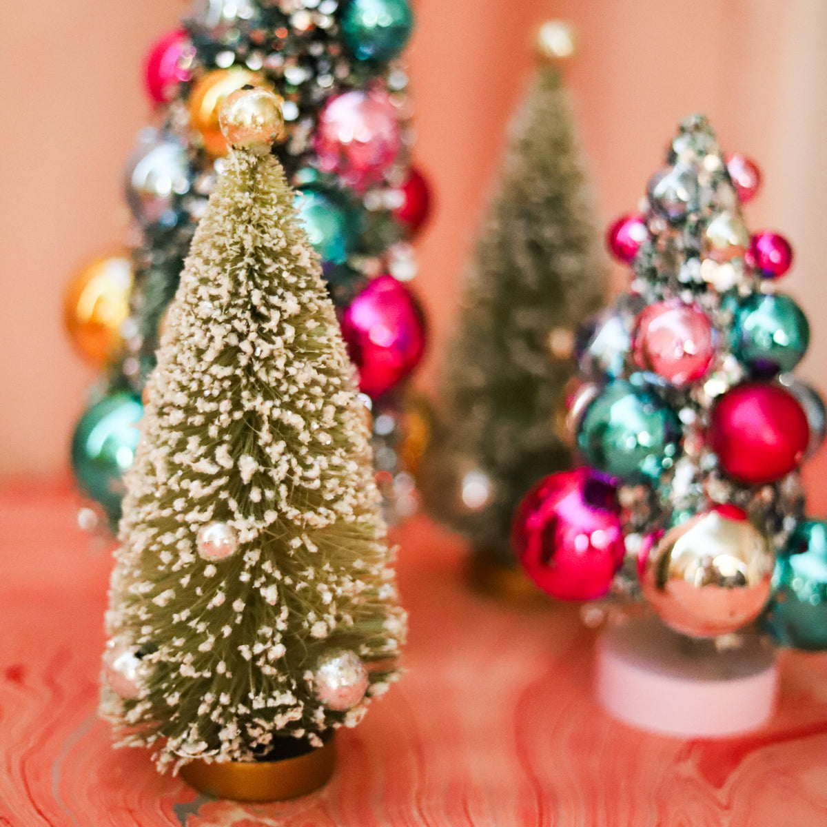 Olive green flocked bottle brush Christmas tree with metallic ornaments. A charming 7-inch accent for mantels, villages, tablescapes, and holiday displays.