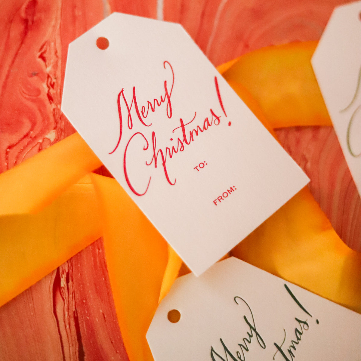Shop Merry Christmas Gift Tags in sets of 8, featuring elegant hand-lettered lettering, To and From lines, and coordinating color options for holiday wrapping.