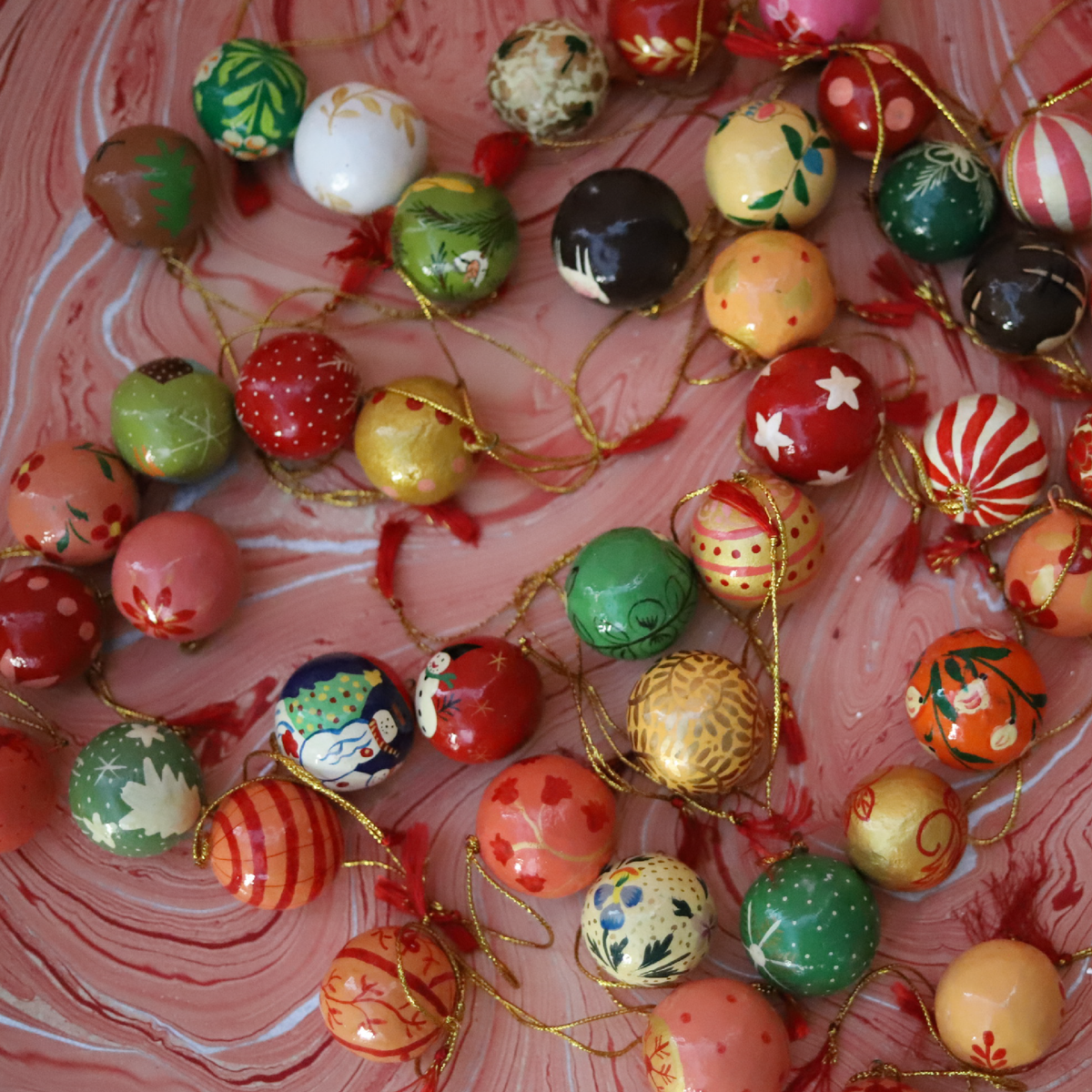 Assorted hand-painted paper mache gift baubles in colorful vintage-inspired Christmas patterns
