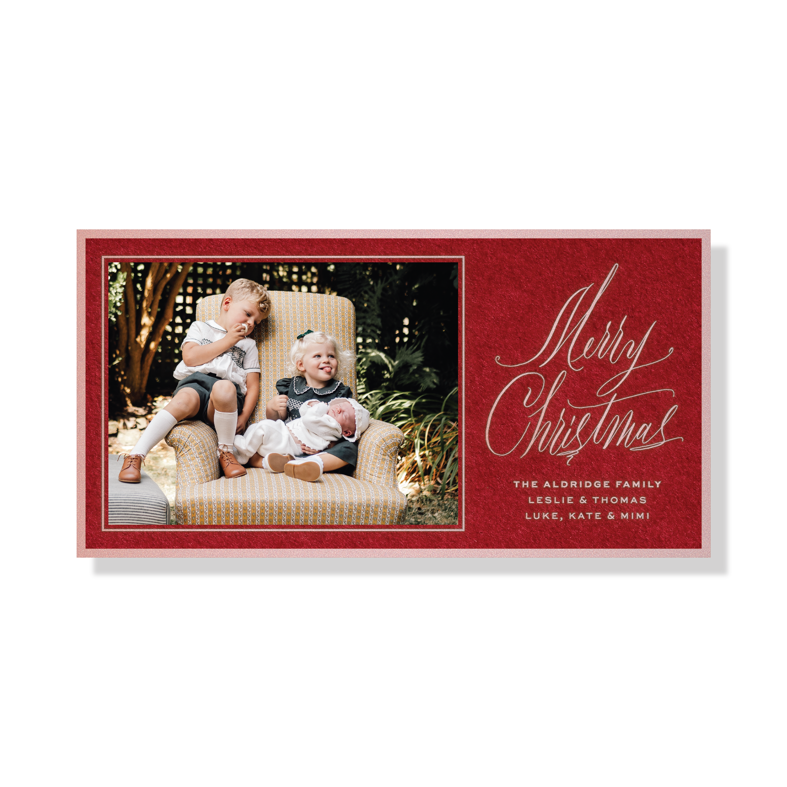 Aldridge Engraved Christmas Photo Card featuring a family photograph beside hand-lettered “Merry Christmas” calligraphy on a rich red background with personalized family names.