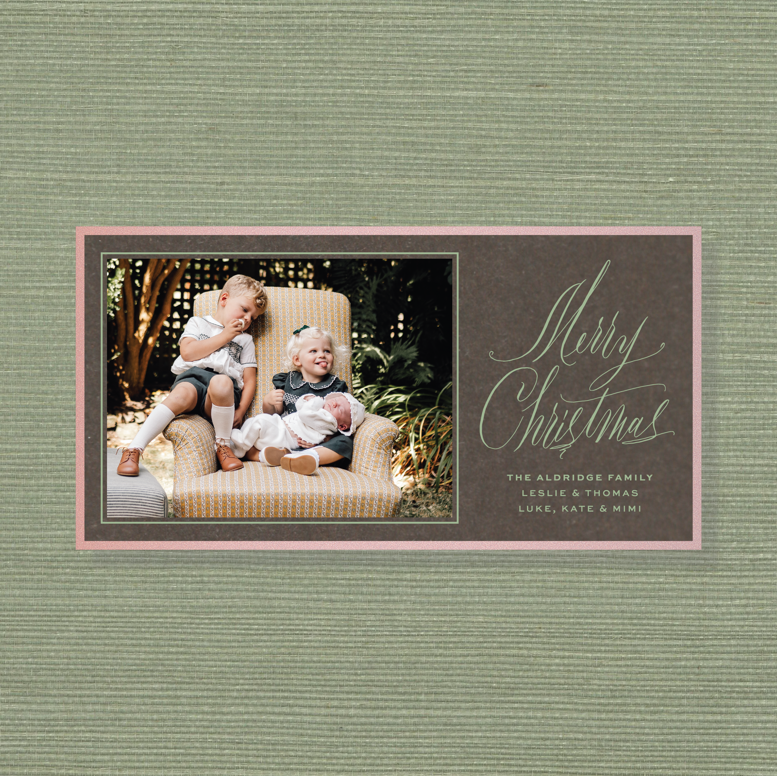Aldridge Engraved Christmas Photo Card featuring a family photograph beside hand-lettered “Merry Christmas” calligraphy on a rich red background with personalized family names.