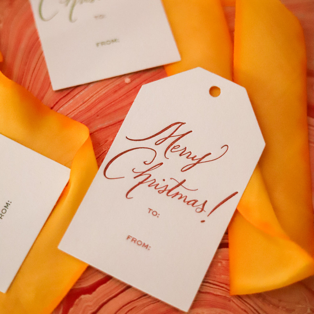 Shop Merry Christmas Gift Tags in sets of 8, featuring elegant hand-lettered lettering, To and From lines, and coordinating color options for holiday wrapping.