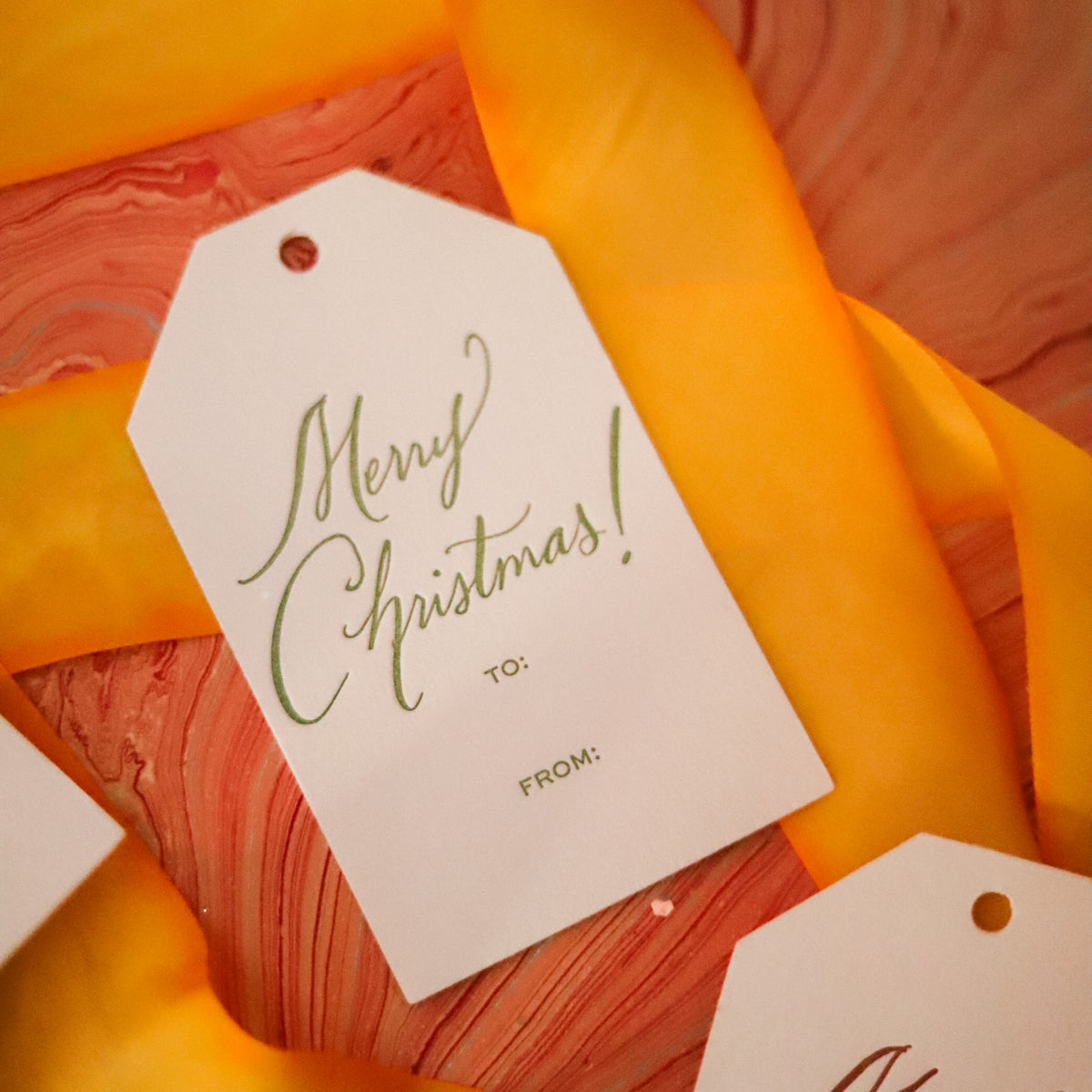 Shop Merry Christmas Gift Tags in sets of 8, featuring elegant hand-lettered lettering, To and From lines, and coordinating color options for holiday wrapping.