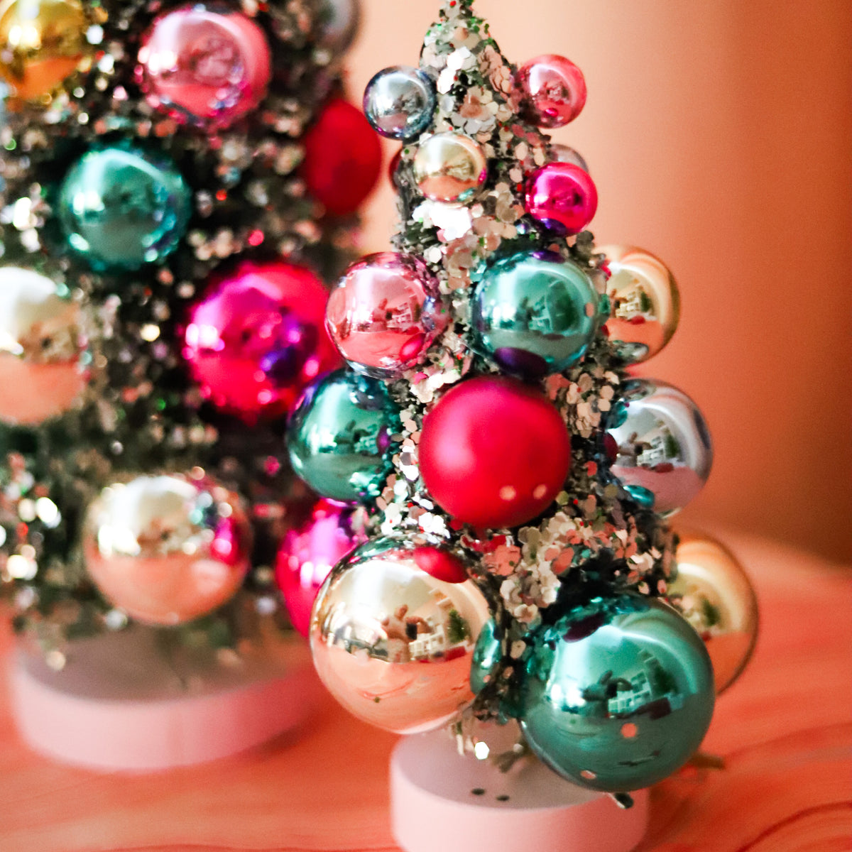 Colorful bauble bottle brush Christmas trees with snowy flocking and shimmering ornaments. A festive accent for mantels, villages, tablescapes, and holiday displays.Colorful bauble bottle brush Christmas trees with snowy flocking and shimmering ornaments. A festive accent for mantels, villages, tablescapes, and holiday displays.
