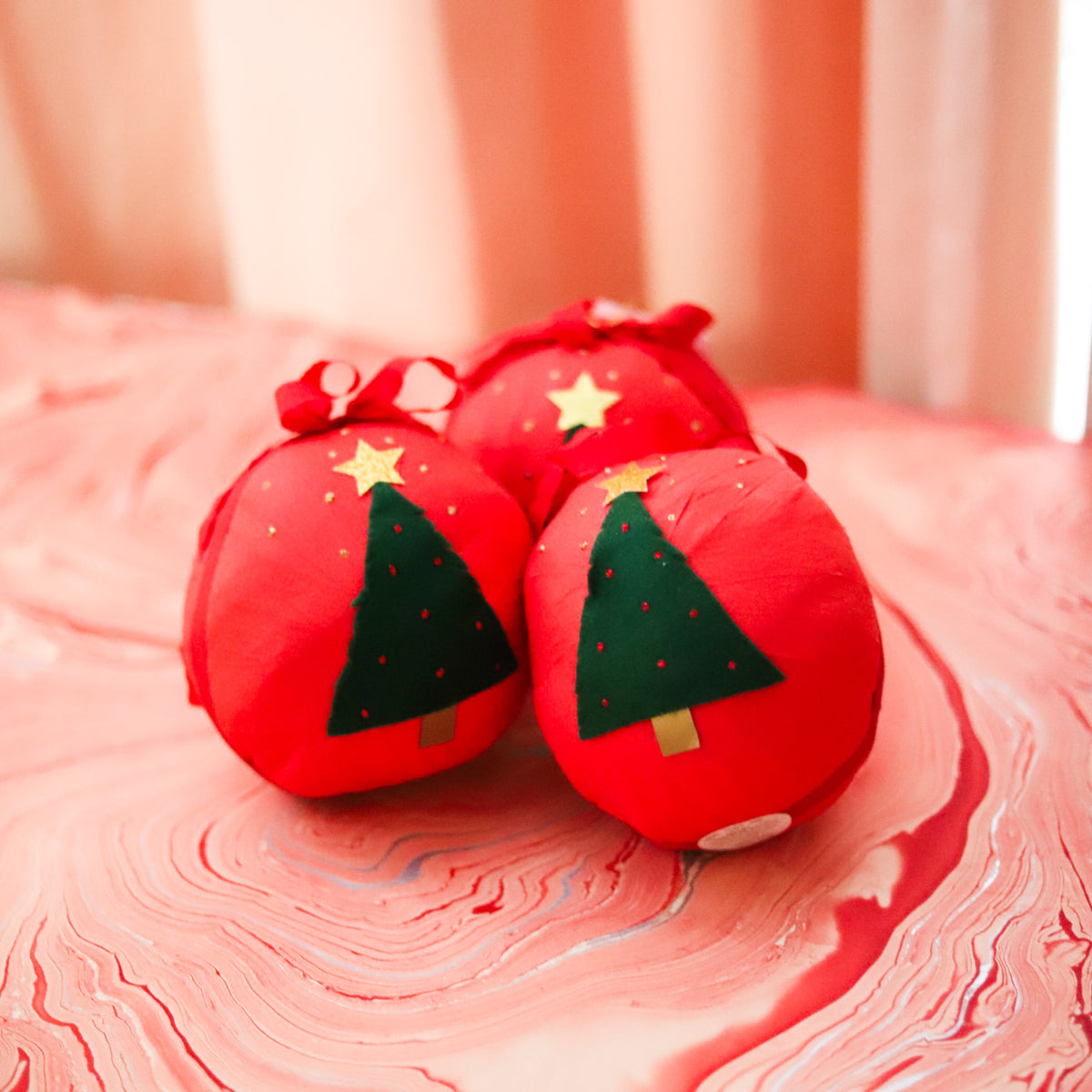 Three red Giant Holiday Surprise Balls with Christmas tree designs displayed together