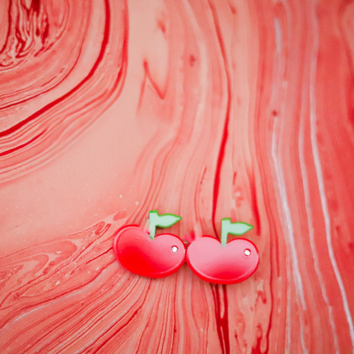 The Cherry Hair Clip features glossy red cherries, green stems and sparkling crystal details, crafted from colorful cellulose acetate.