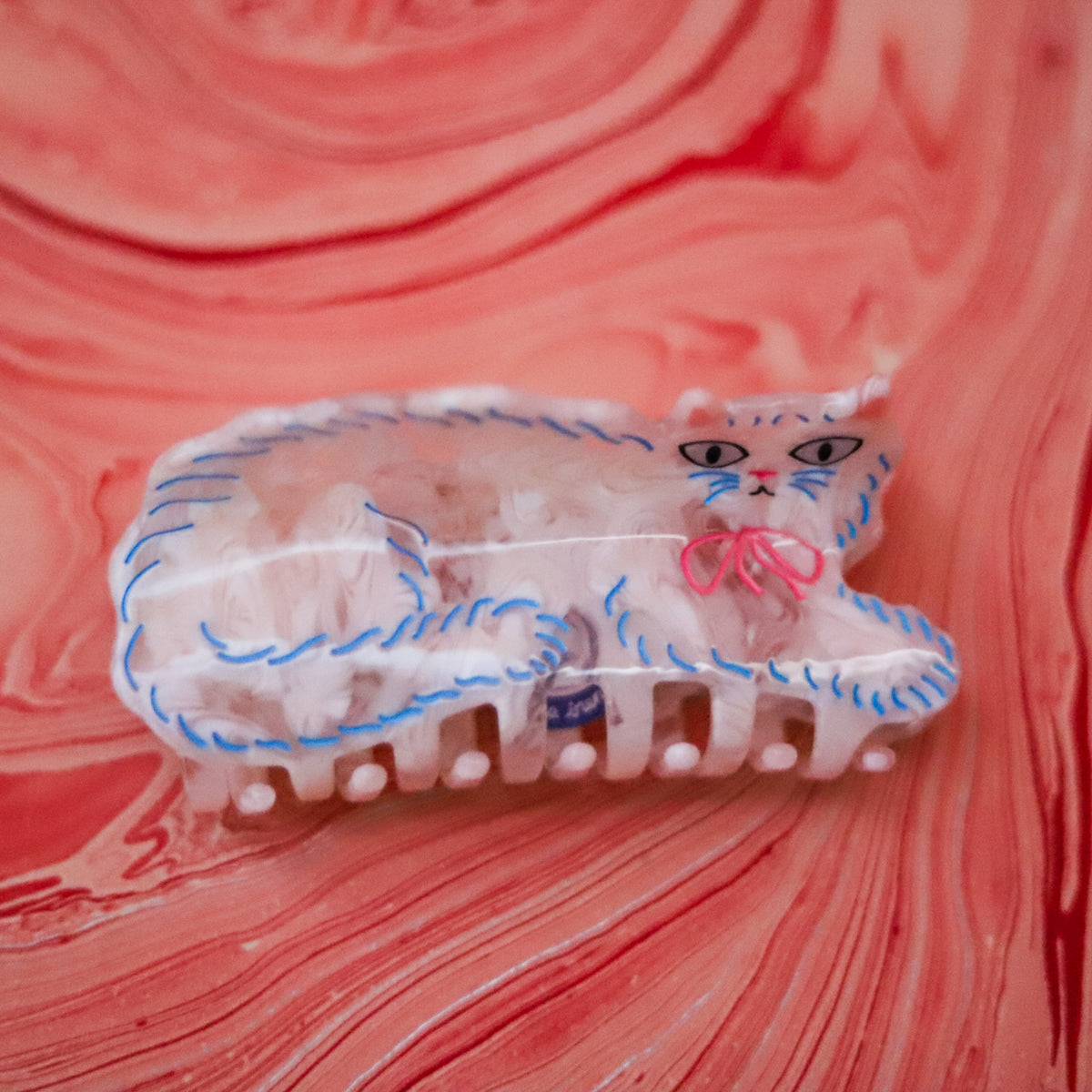 The Pretty Kitty Hair Claw features a fluffy white Persian cat design with hand-painted details, crafted from glossy cellulose acetate.