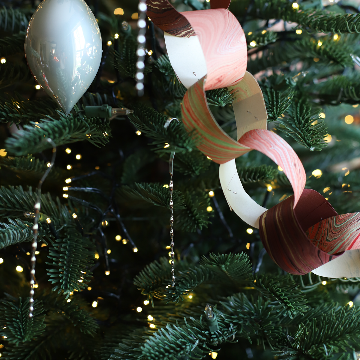 Vintage-style silver tin tinsel icicles decorating a Christmas tree with handmade paper chain garland