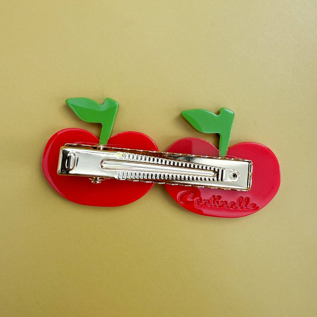 The Cherry Hair Clip features glossy red cherries, green stems and sparkling crystal details, crafted from colorful cellulose acetate.
