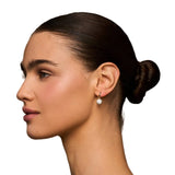 Woman with a stylish hair bun wearing earrings against a neutral background