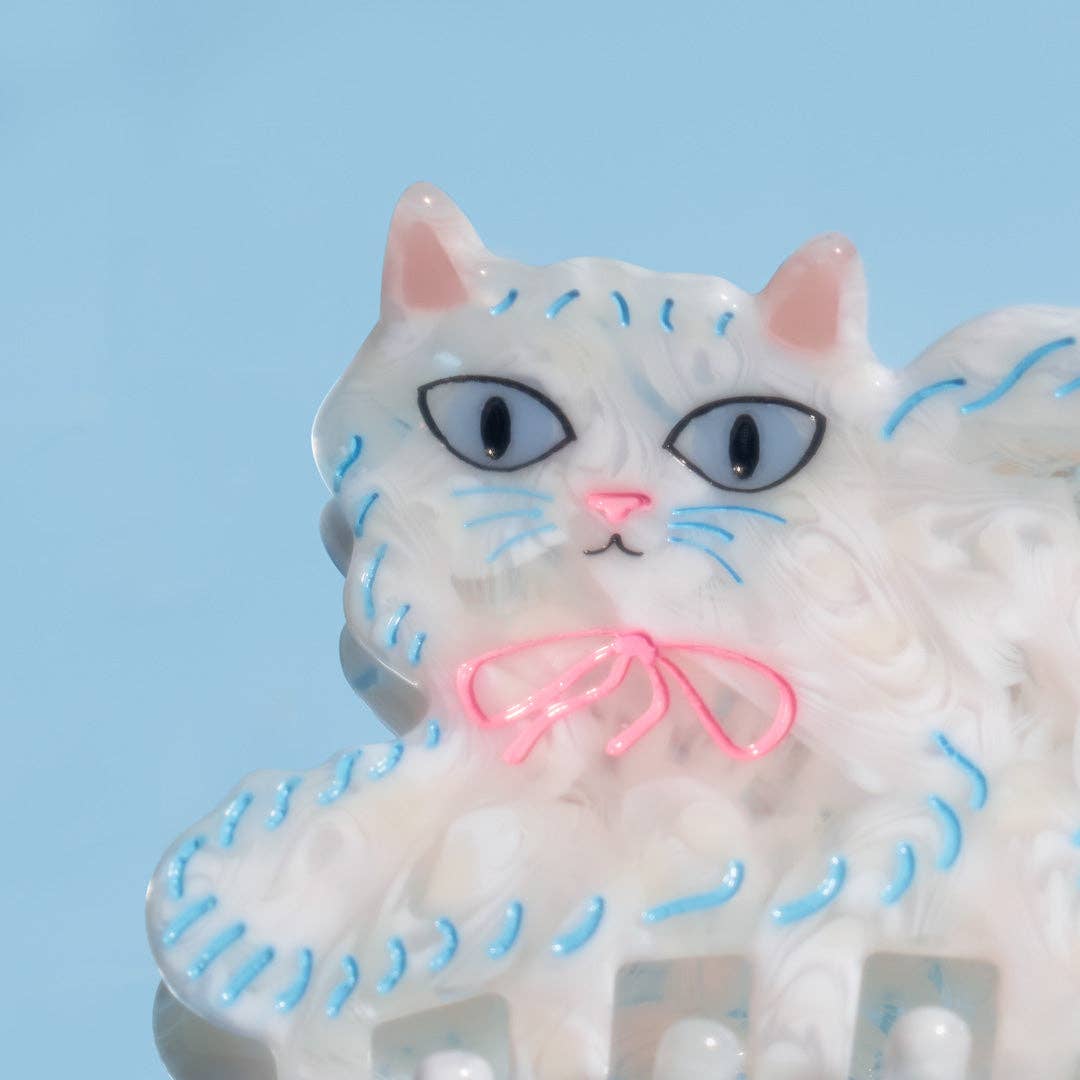 The Pretty Kitty Hair Claw features a fluffy white Persian cat design with hand-painted details, crafted from glossy cellulose acetate.
